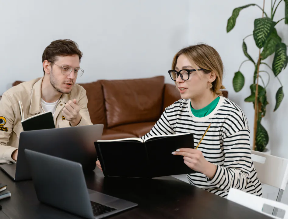 un homme et une femme assis à une table avec des ordinateurs portables